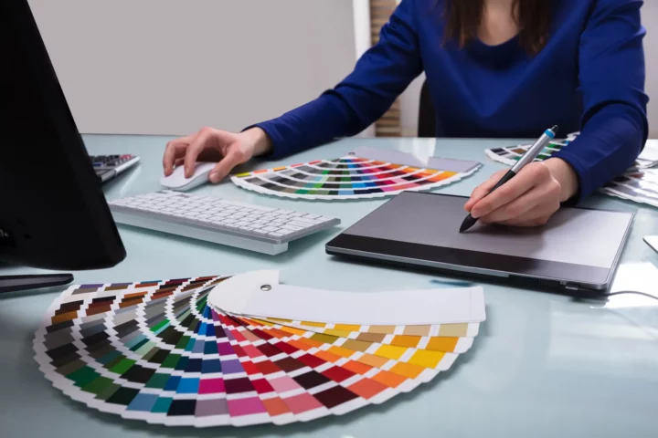 Designer working with graphic tablet and colour swatches